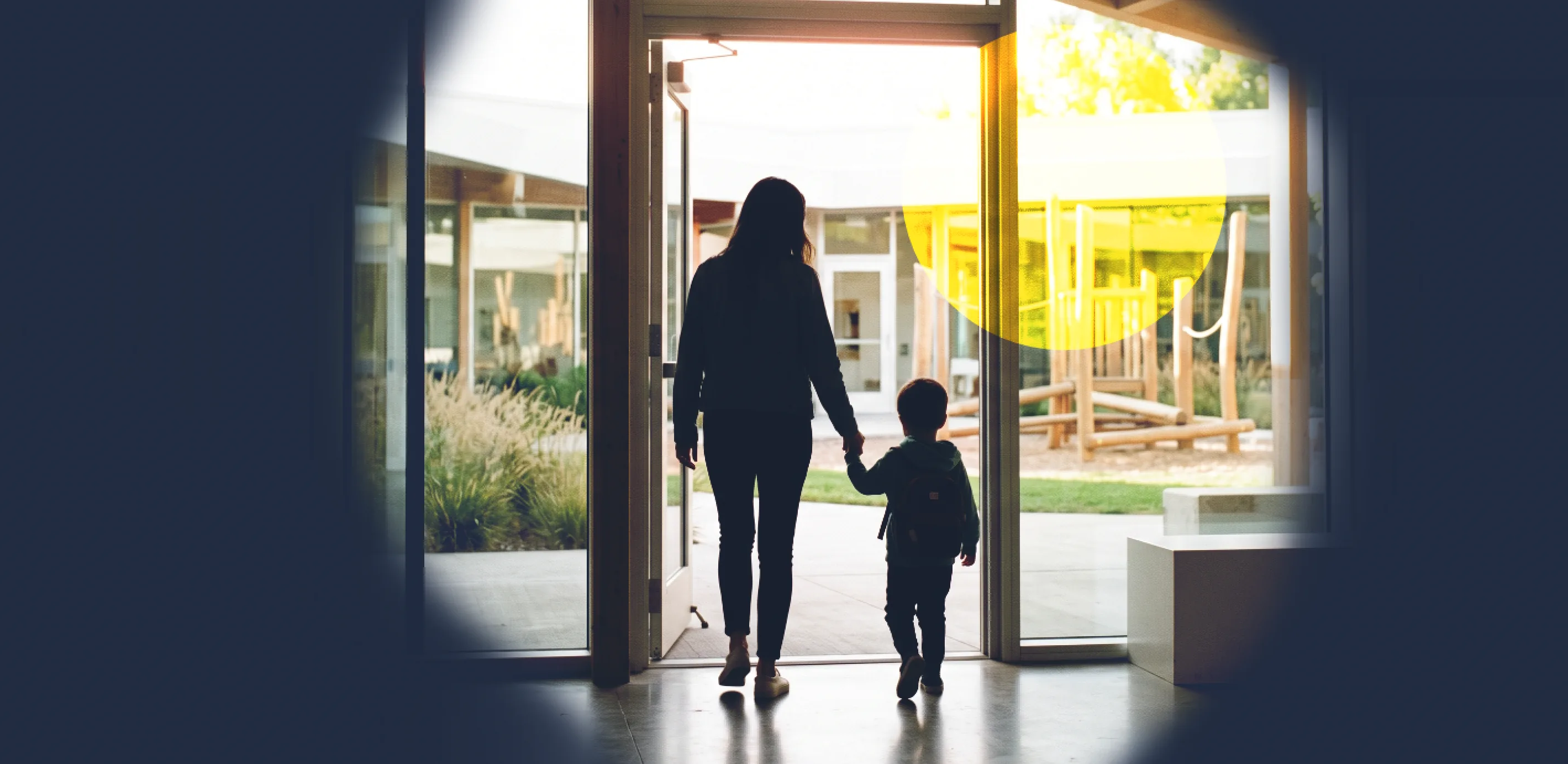 A parent and a small child walking out through the centre's front doors into the afternoon light.